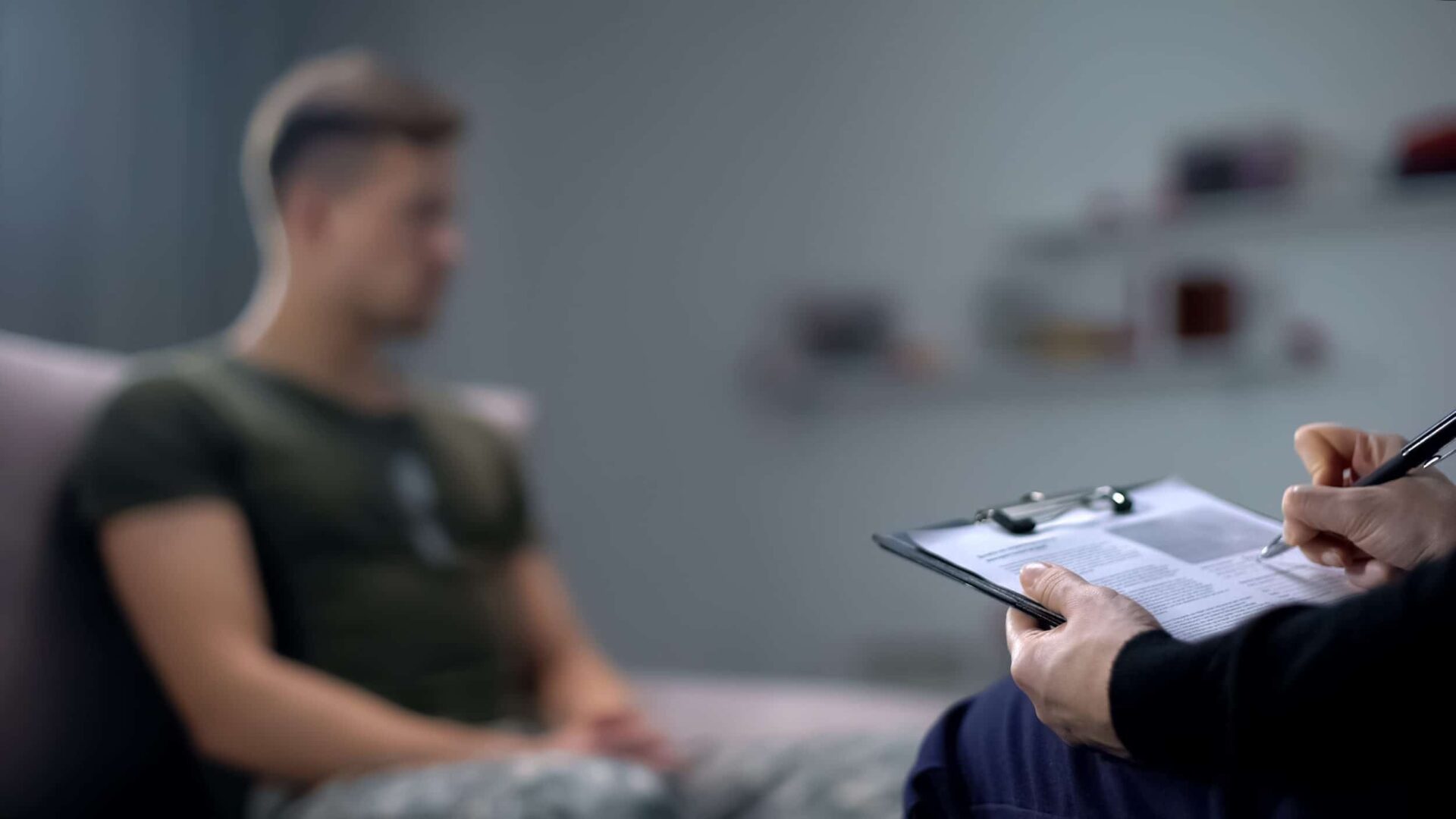 Psicólogo tomando notas durante sesión de terapia con hombre triste s