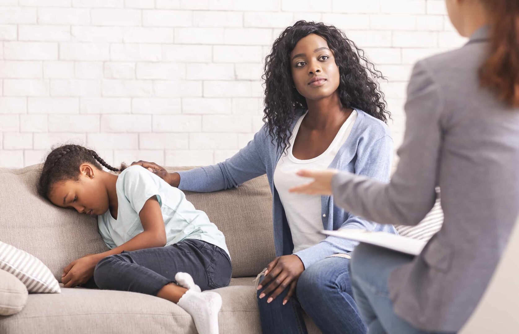 Una madre negra consuela a su hija pequeña en la consulta del psicólogo